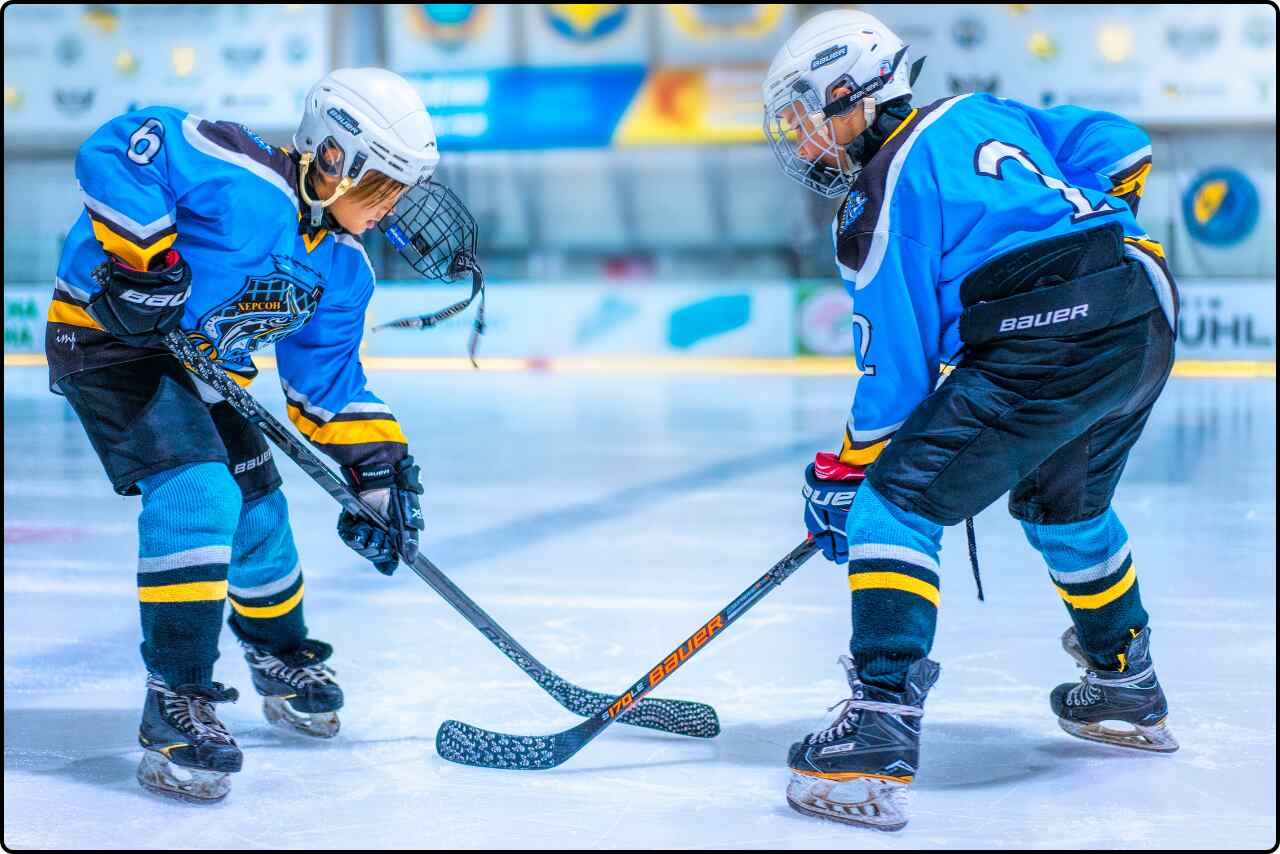 Photograph of two hockey players in a game situation, with one player skating away from the puck while other is in defense.